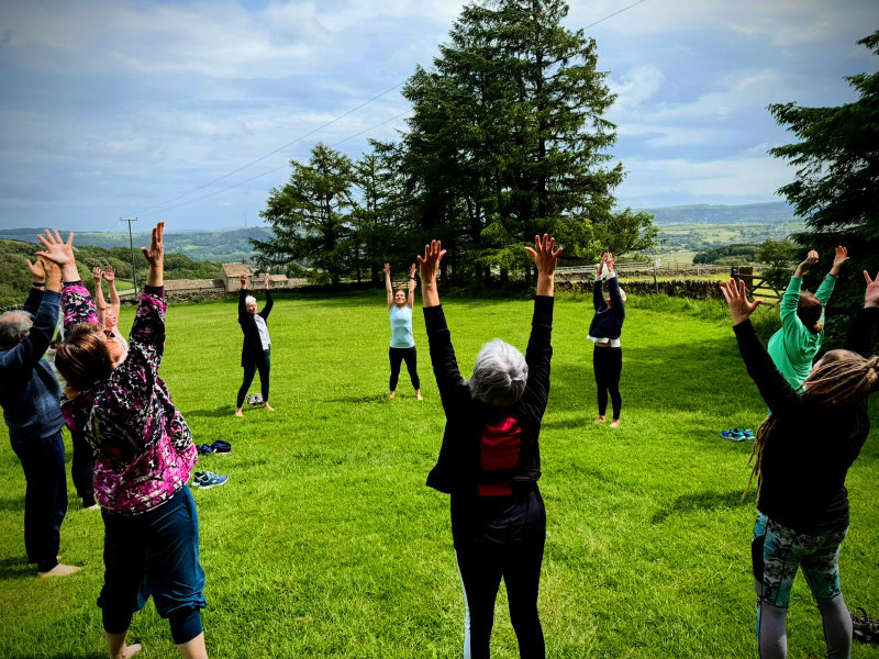 Yoga Connections image - yoga students outside, in a circle, in sun salutation pose